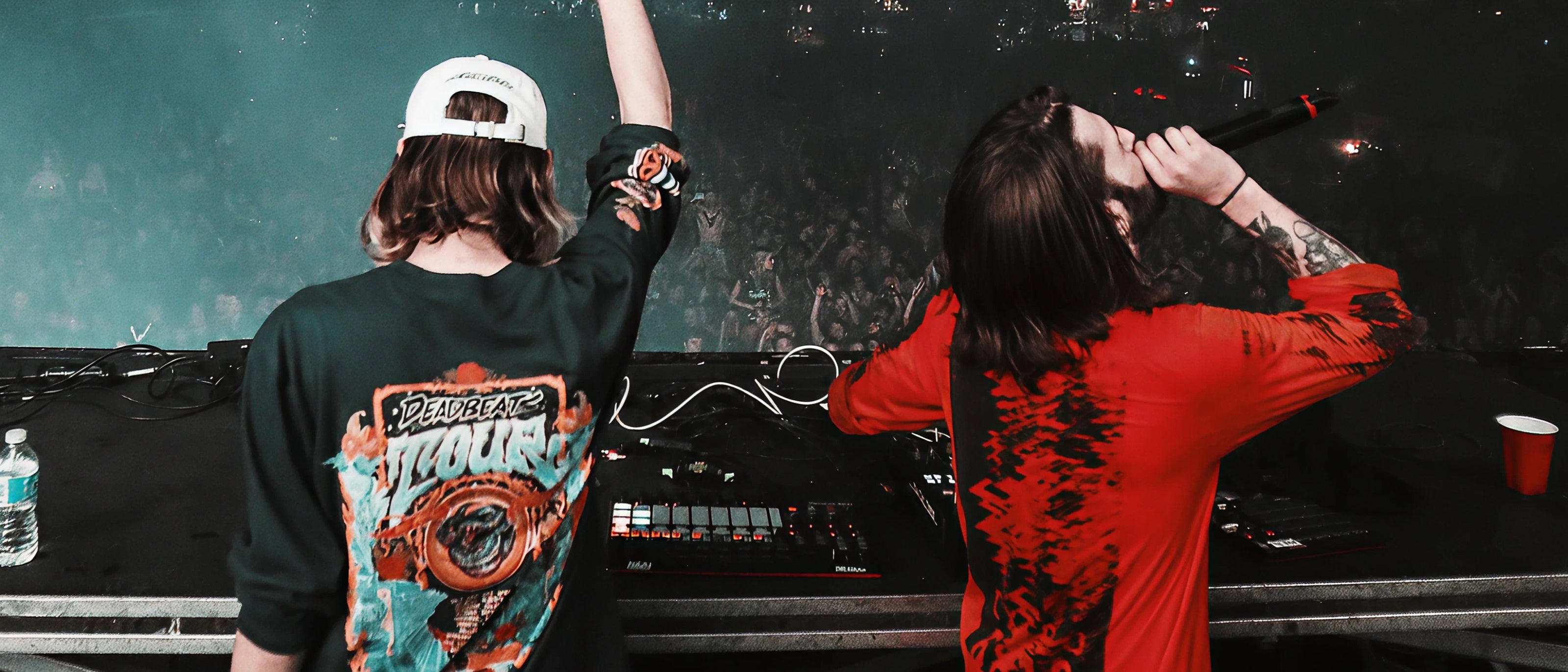 Two people on a stage with one holding a microphone, against a dark background.